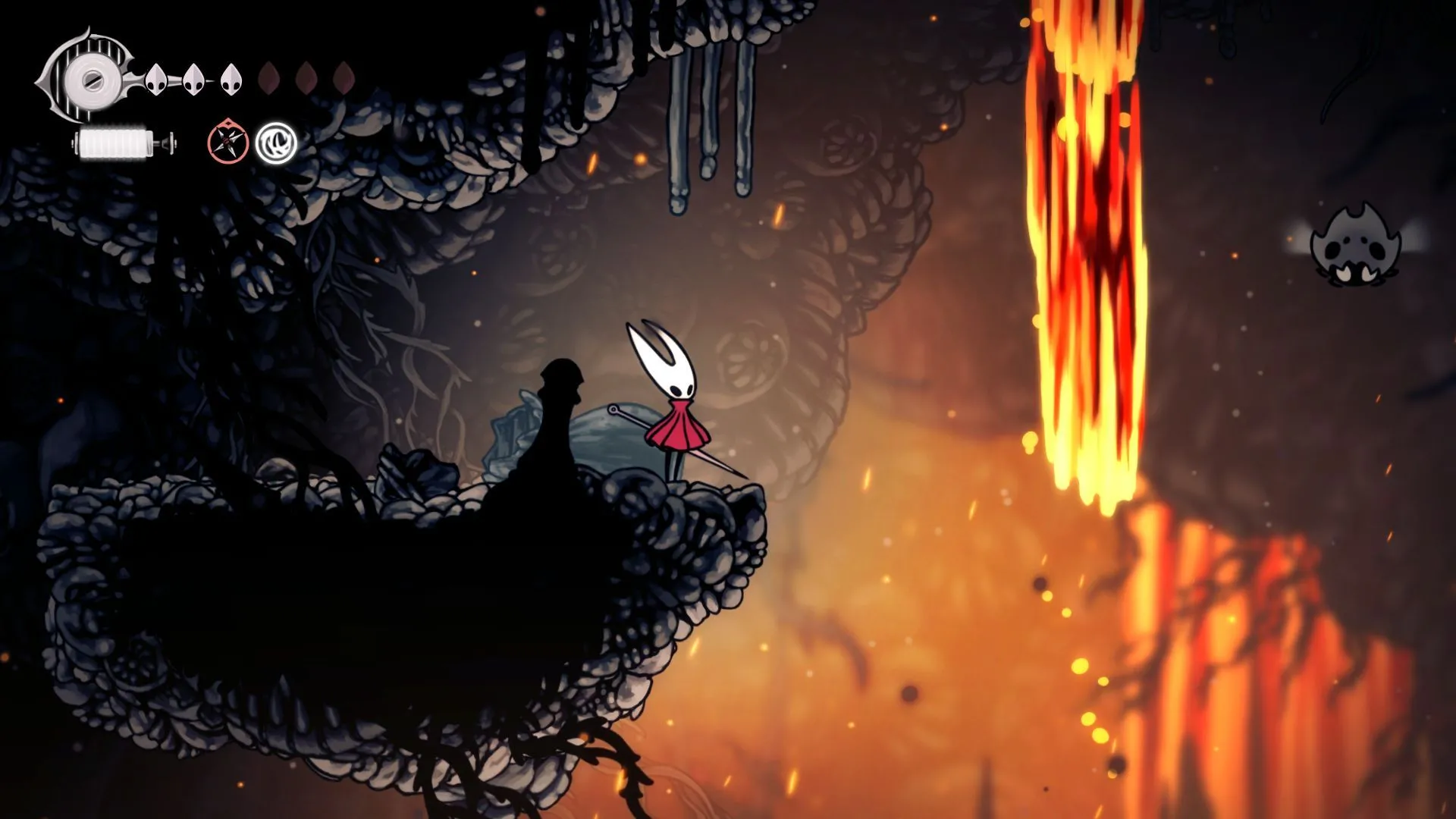 Hornet đứng giữa một khu vực đầy dung nham đỏ rực, đeo chiếc mặt nạ độc đáo trong Hollow Knight Silksong